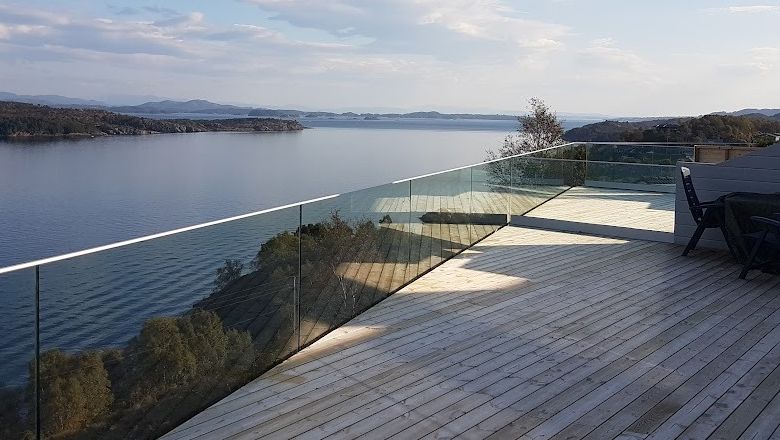 Helglass rekkverk på stor platt med utsikt til sjø og berg